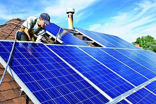 A man putting solar panels on a roof.