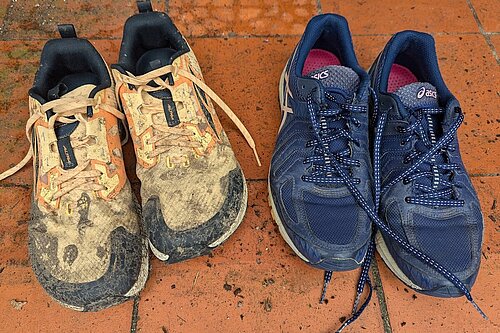 Two pairs of trainers, one muddy