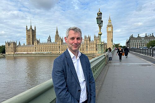 Will Forster with view of Houses of Parliament behind him