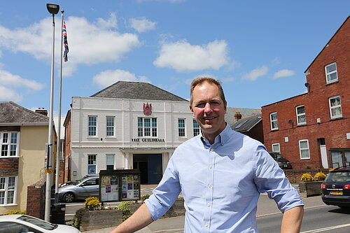 Richard Foord standing in front of Axminster Guildhall on a sunny day