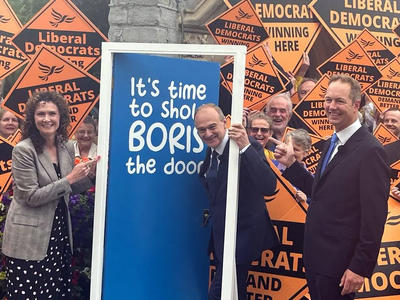 Lib Dem leader Ed Davey posing with a blue door to send a message to Boris Johnson