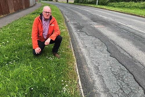 Councillor Fenton by a large pothole