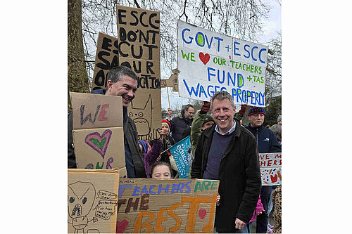 James with parents and children, and a variety of home made signs "ESCC don't cut our education", "Govt + ESCC we love our teachers and TAs. Fund wages properly", "Teachers are the best". There are also some uncomplimentary pictures of politicians.