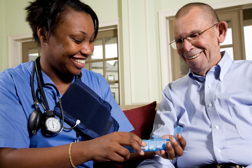 Nurse offering medication to old man.