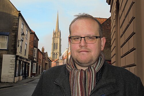 Lib Dem Candidate for Louth and Horncastle Ross Pepper standing in front of St James' Church