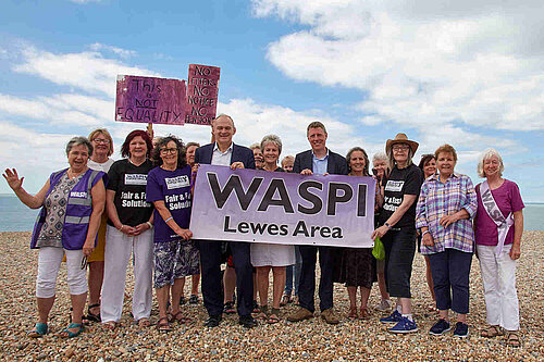 James and Ed with a group of women, all facing the camera, and holding a large sign that says "Waspi Lewes Area". Several of the women are wearing t-shirts with "Fair and fast solution"