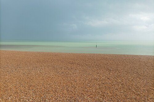 Stony beach with threatening cloud over sea.