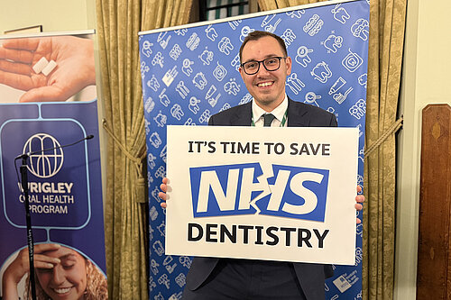 Tom Gordon stood with a sign reading 'It's time to save NHS Dentistry'