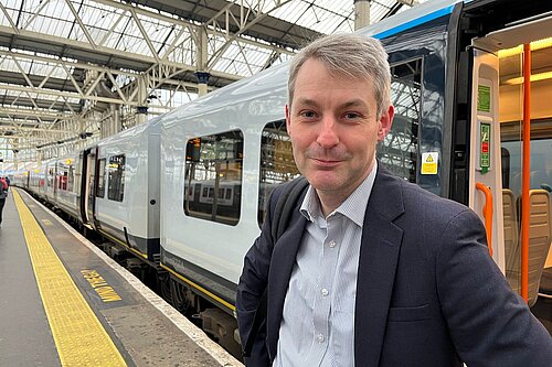 Will Forster stood next to a train