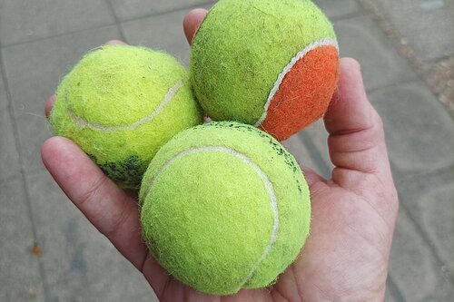 Three tennis balls held in hand