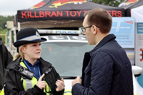 Tom Gordon speaking to a policewoman in front of a police van