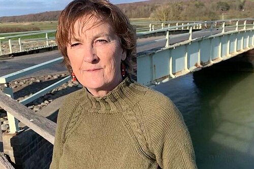 Carolyn Lambert on a sunny day with the Exceat bridge behind her